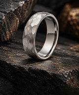 Silver hammered tungsten wedding ring on dark textured stone