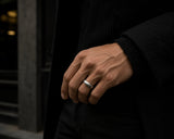 Man wearing a hammered silver tungsten wedding ring with dark luxury menswear styling and moody cinematic lighting