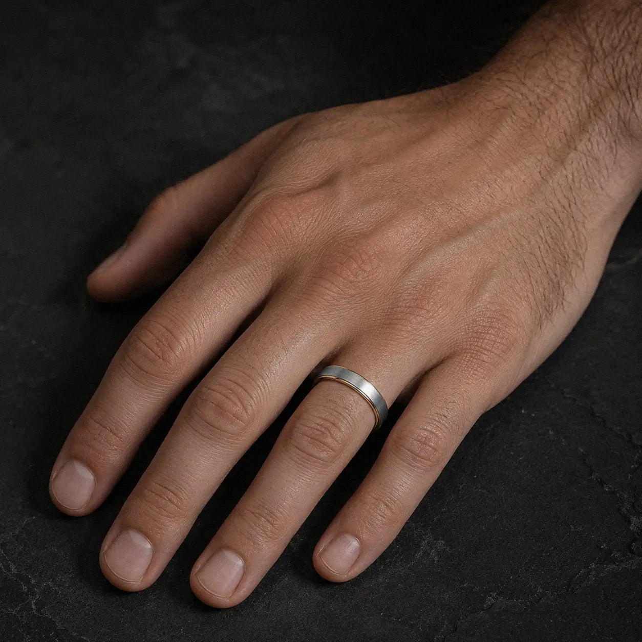 Man wearing an 4mm brushed silver tungsten wedding ring with polished gold inner band