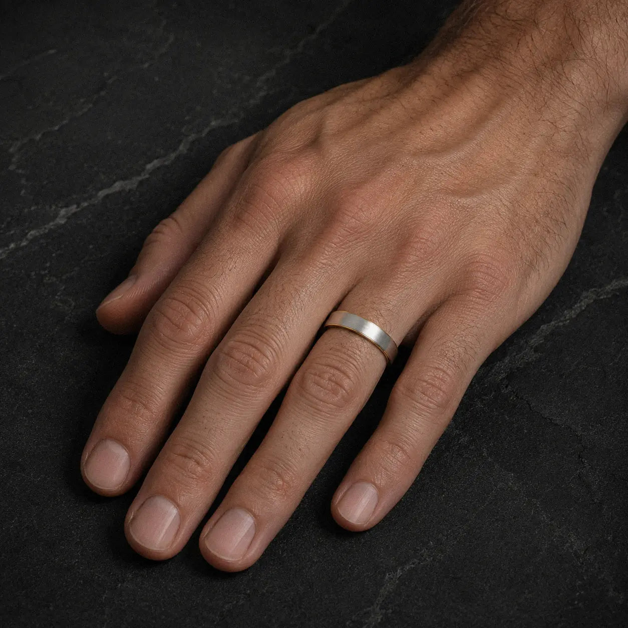 Man wearing an 8mm brushed silver tungsten wedding ring with polished black inner band
