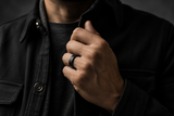 Man wearing a matte black wedding band in a dark editorial lifestyle portrait.