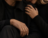 Couple wearing matching polished gold wedding bands in a luxury cinematic lifestyle setting