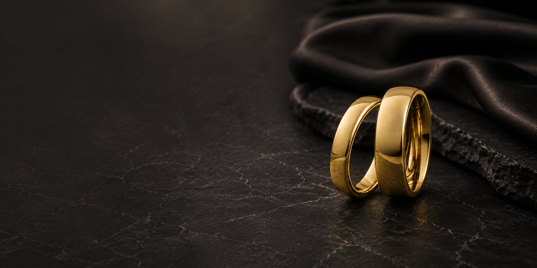 Luxury gold matching wedding bands hero banner with dark moody background and space for text overlay