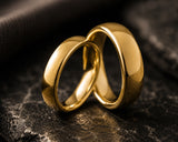 Ultra close-up macro photograph of polished gold matching wedding bands with visible reflective detail and luxury texture