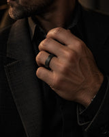 Man wearing a black brushed tungsten wedding ring while adjusting a dark tailored jacket.