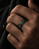 Man wearing a black tungsten wedding ring with a natural green moss agate inlay.