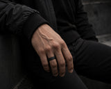 Man wearing a black silicone wedding ring with modern dark casual styling and cinematic luxury lighting