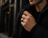 Man wearing a black tungsten and oak wood wedding ring with dark modern outfit in premium urban lifestyle photography.