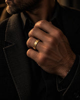 Man wearing a brushed gold tungsten wedding ring with a dark tailored jacket.