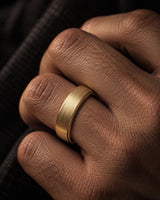 Macro close-up of a brushed gold tungsten wedding ring worn on a man’s ring finger.