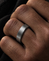 Macro close-up of a men’s gunmetal grey brushed tungsten wedding ring worn on the ring finger.