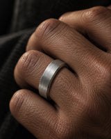 Close-up of a men’s silver brushed tungsten wedding ring worn on the ring finger.