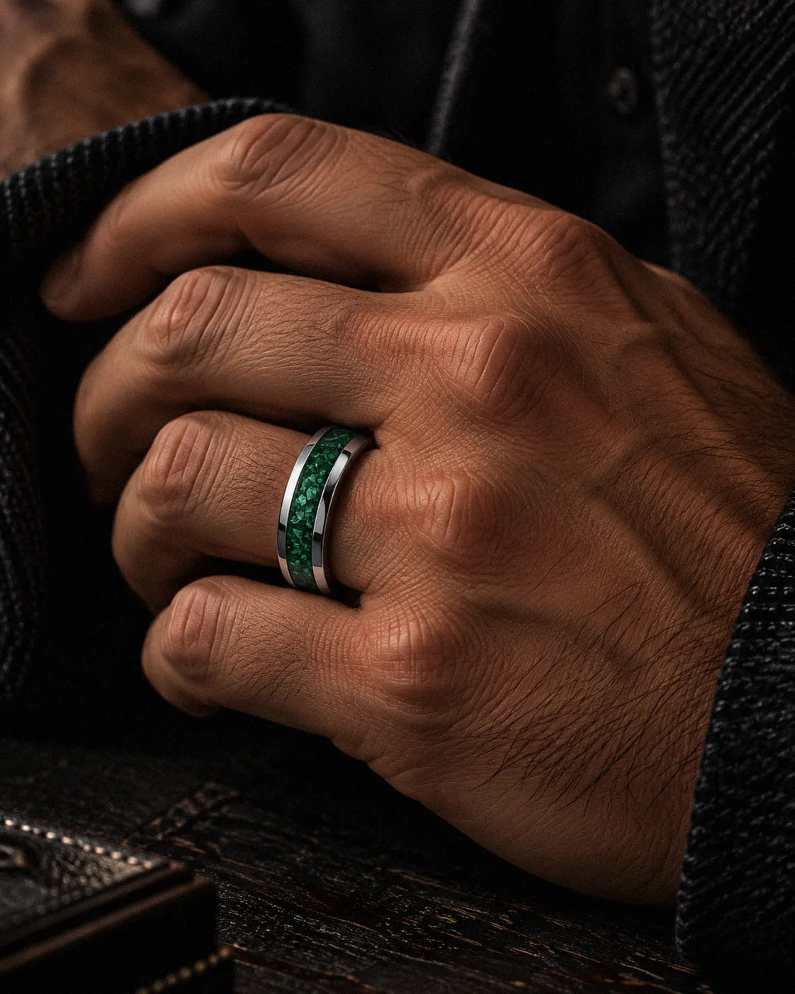Man wearing a silver tungsten wedding ring with green emerald gemstone inlay