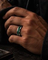 Man wearing a silver tungsten wedding ring with green emerald gemstone inlay