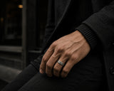 Man wearing a brushed silver titanium wedding ring with dark luxury styling and cinematic urban fashion aesthetic.