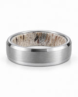 Brushed silver tungsten wedding ring lying flat showing natural antler inner sleeve