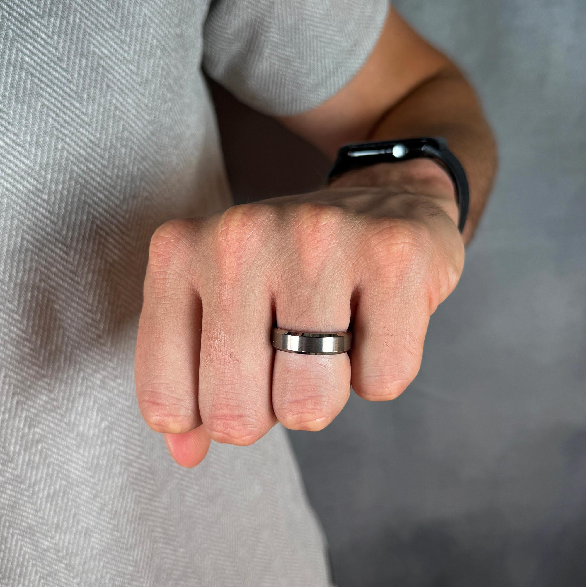 Close-up of a person's fist wearing a silver ring on a neutral background