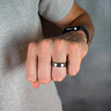 Close-up of a person's fist wearing a silver ring on a neutral background