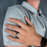 Person wearing a gray shirt jacket with a hand on their shoulder, wearing a silver ring.