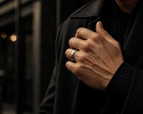 Man wearing a brushed silver tungsten wedding ring with dark modern clothing in a premium urban lifestyle setting