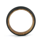 Side profile of a men's black tungsten wedding band with a real whiskey barrel wood inlay.