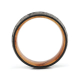 Side profile of an 8mm men's black tungsten wedding band with a forest engraving and real wood inlay.