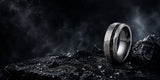 Silver meteorite tungsten wedding ring positioned on dark volcanic stone with atmospheric cinematic background and space-inspired masculine styling