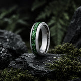 Luxury moss agate wedding ring collection hero image featuring a polished silver tungsten ring with green moss agate inlay on a dark cinematic forest-inspired stone background.