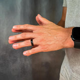 Hand with a ring and smartwatch on a gray background