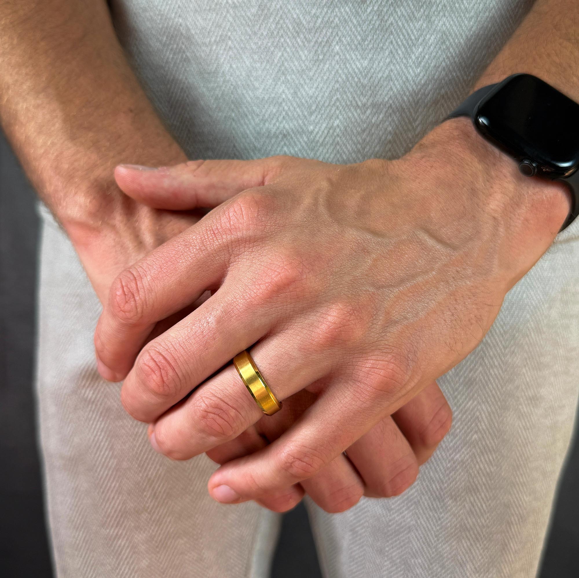 Close-up of hands with a gold ring on a neutral background
