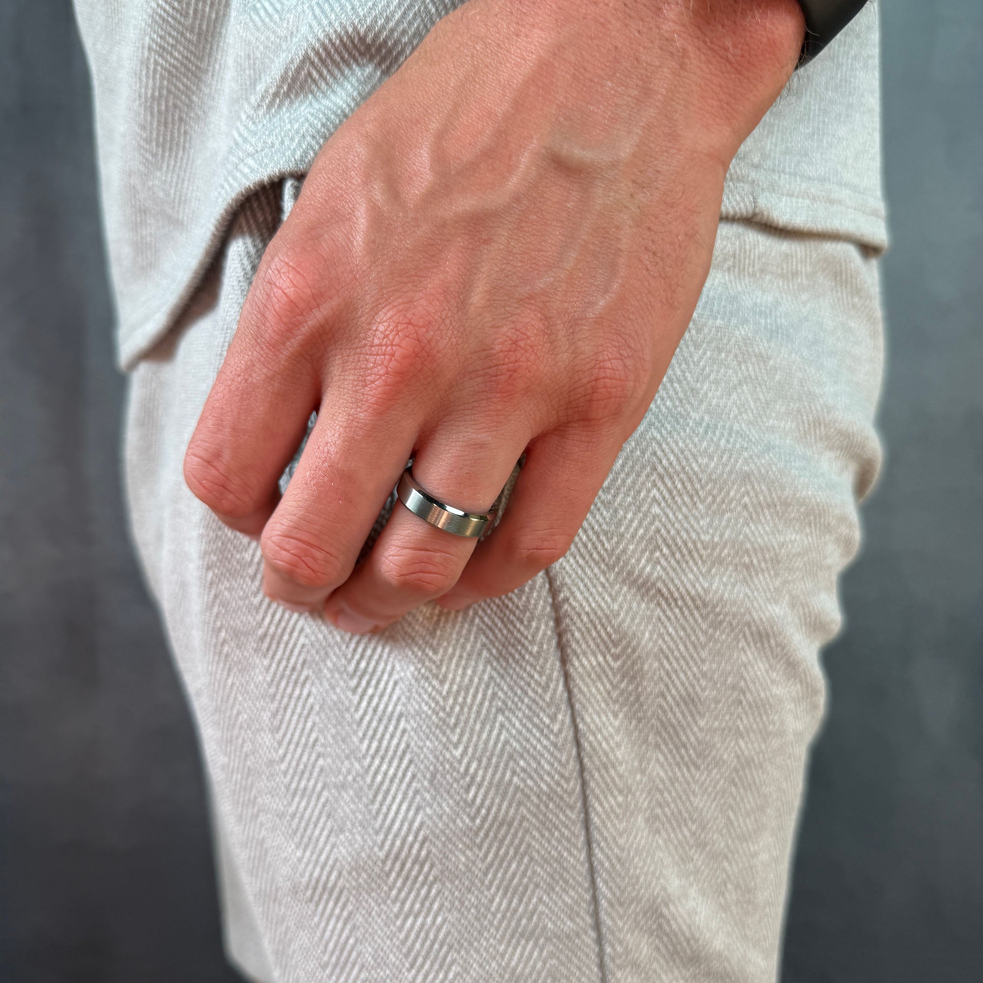 Close-up of a hand wearing a silver ring on a neutral background