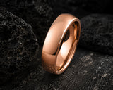 Macro close-up of a polished rose gold men’s wedding ring on dark volcanic stone with detailed luxury craftsmanship lighting