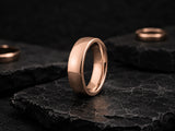 Rose gold domed men’s wedding ring on dark volcanic rock with cinematic luxury lighting