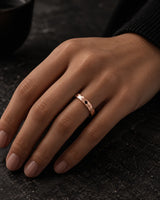 Rose gold faceted tungsten wedding ring lying flat, showing the diamond-cut finish