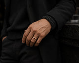 Man wearing a polished rose gold wedding ring with dark luxury fashion styling and cinematic urban atmosphere