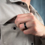 a man putting something in his chest pocket wearing a brushed black titanium ring