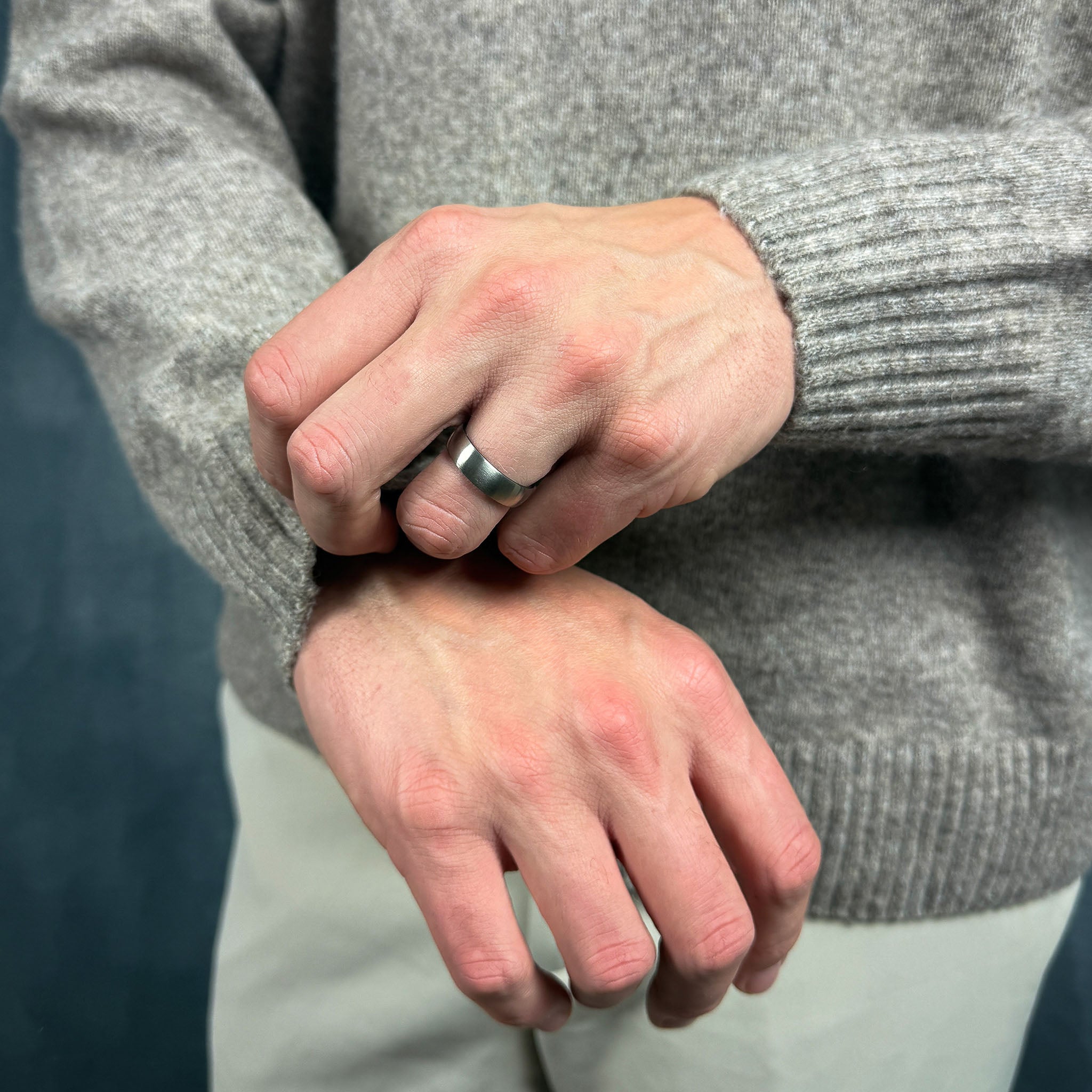 Close-up of a man adjusting his sleeve wearing a brushed titanium and blue ring