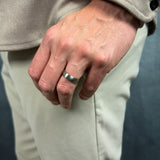 a mans hand held down by his pocket wearing a brushed silver titanium wedding ring