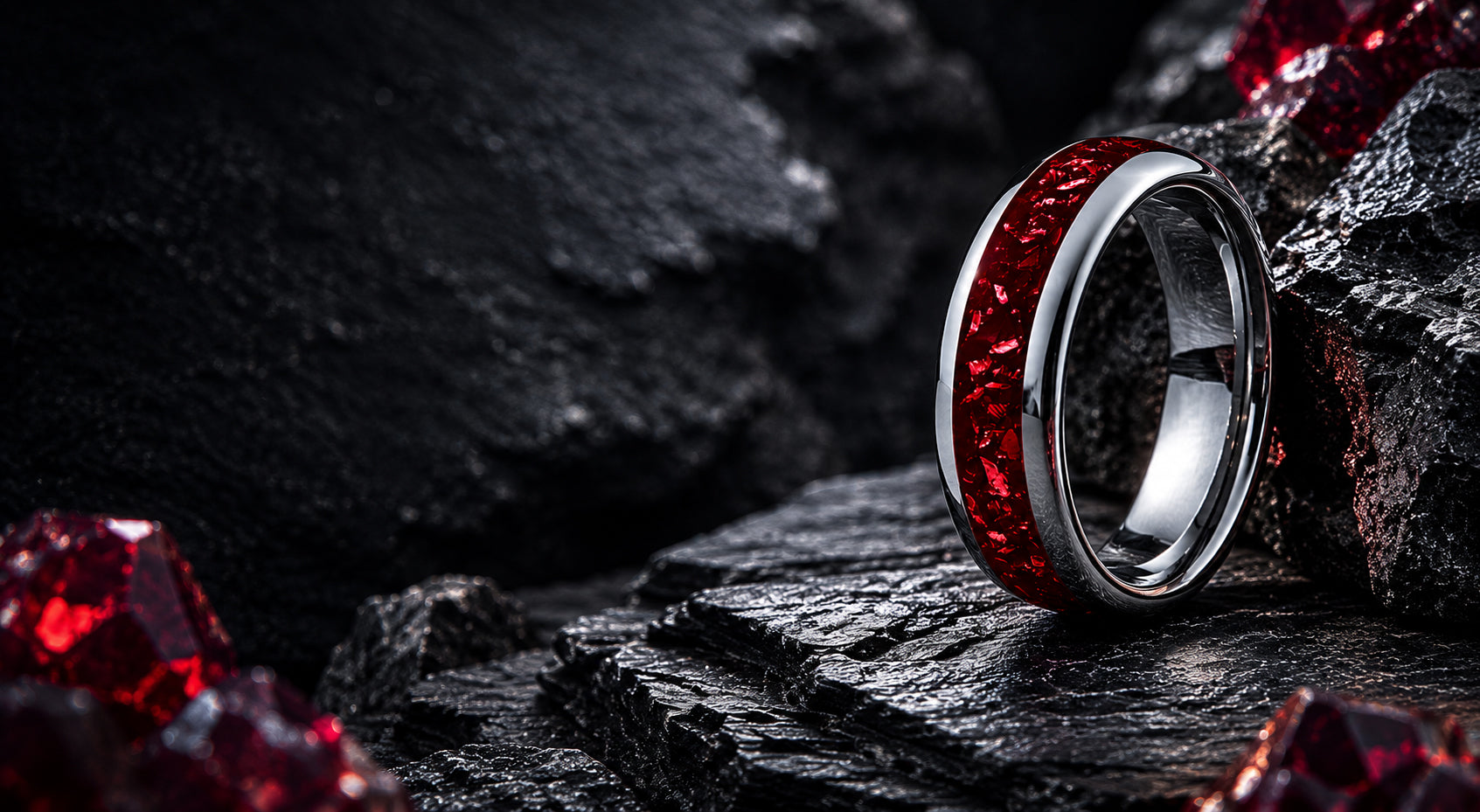 Luxury desktop banner for ruby wedding rings collection featuring a silver tungsten ring with deep red ruby inlay positioned on a dark cinematic stone background.