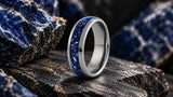 Silver sapphire gemstone wedding ring on dark textured stone