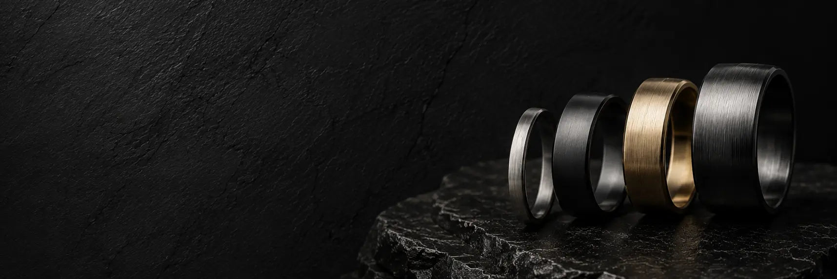 Men's wedding ring width comparison featuring 2mm, 4mm, 6mm and 8mm bands displayed on dark slate stone in a luxury masculine jewellery setting.