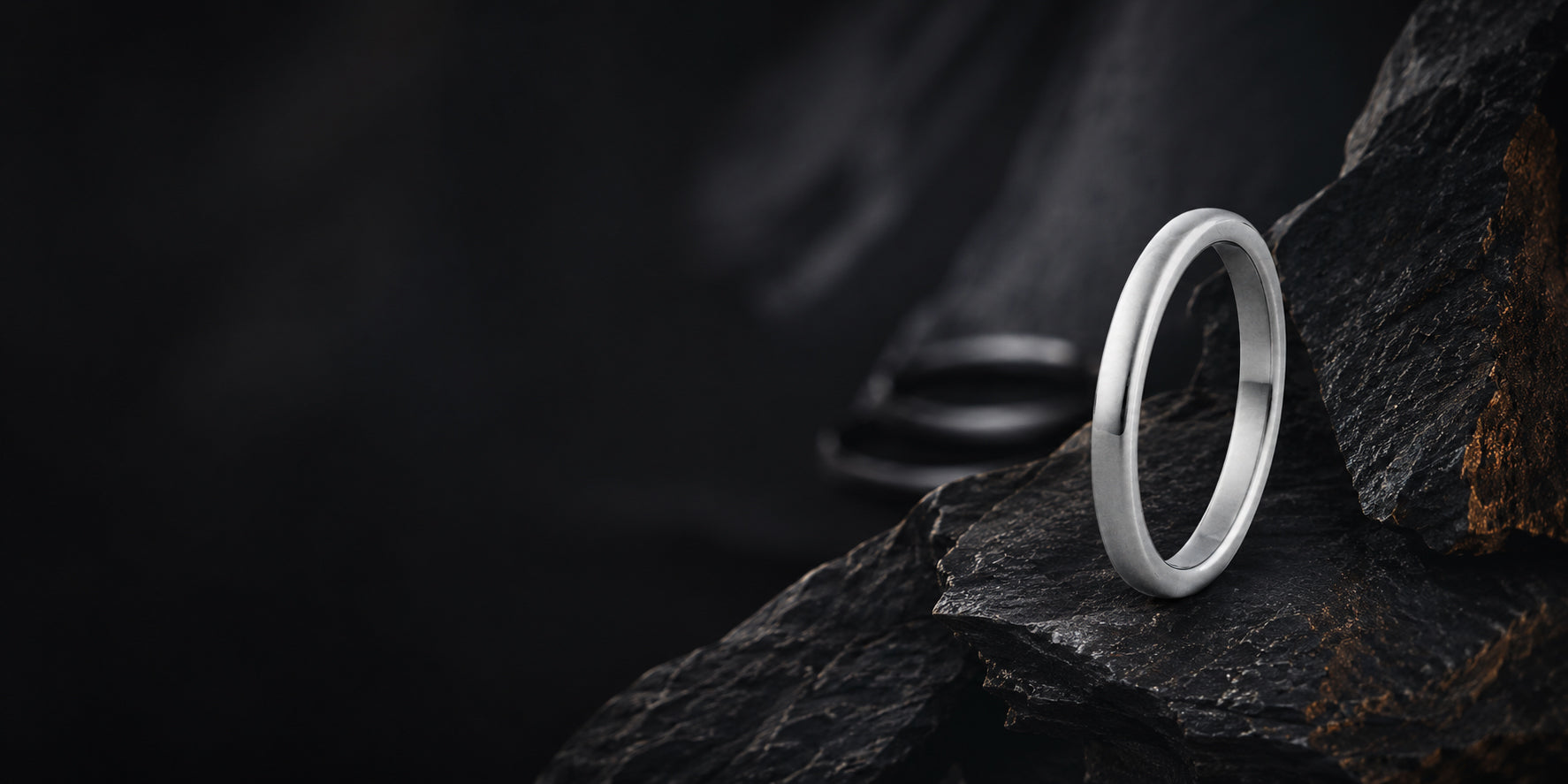Minimalist silver 2mm dome wedding ring hero banner with dark slate background and cinematic lighting