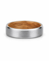 Silver beveled tungsten wedding ring with whiskey barrel wood inner sleeve photographed from a low front angle on a white background.