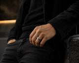 Man wearing a silver titanium wedding ring with blue inner sleeve in a dark cinematic lifestyle setting