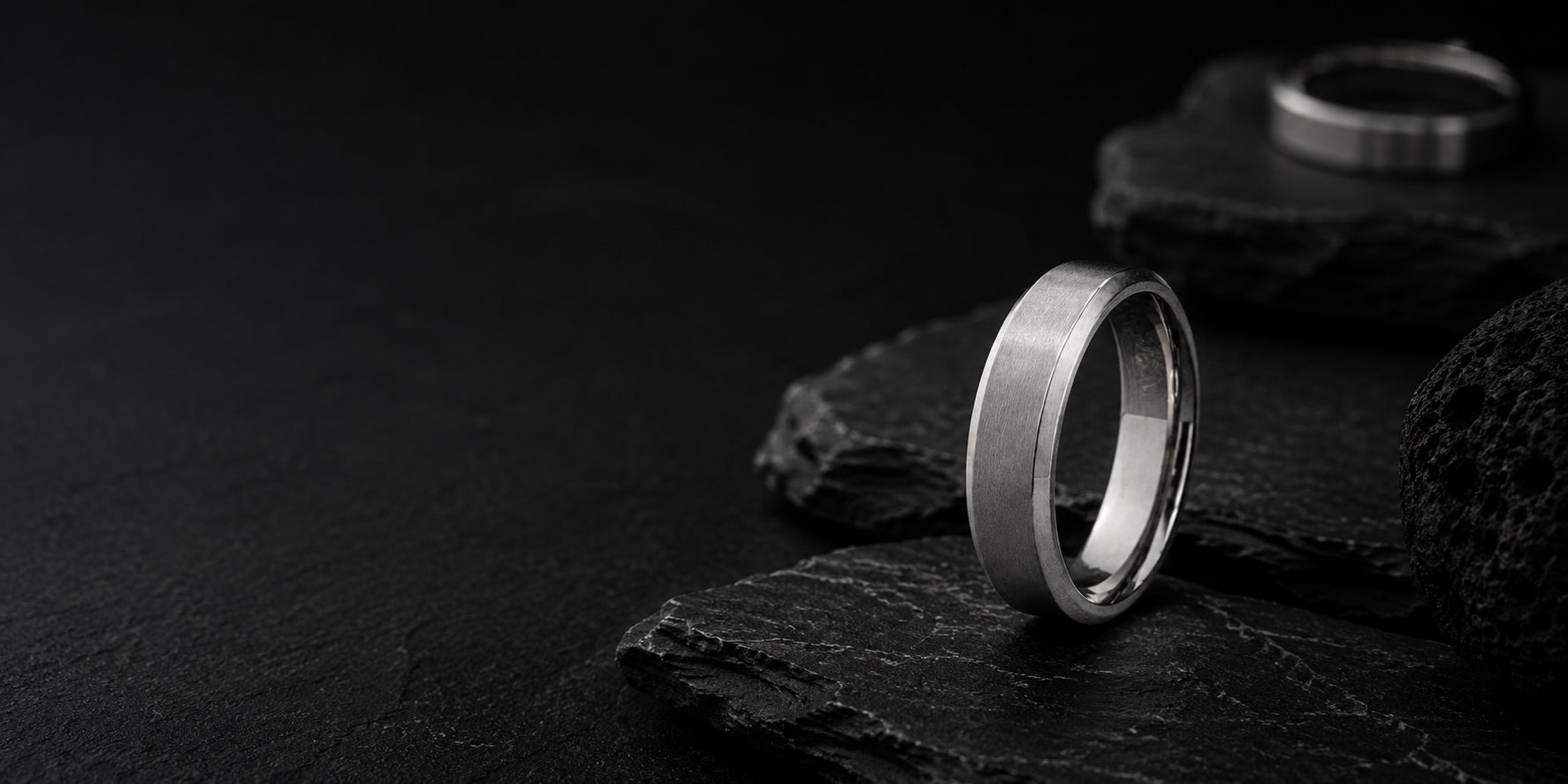 Luxury silver titanium men’s wedding ring hero banner with dark charcoal textures and premium editorial lighting