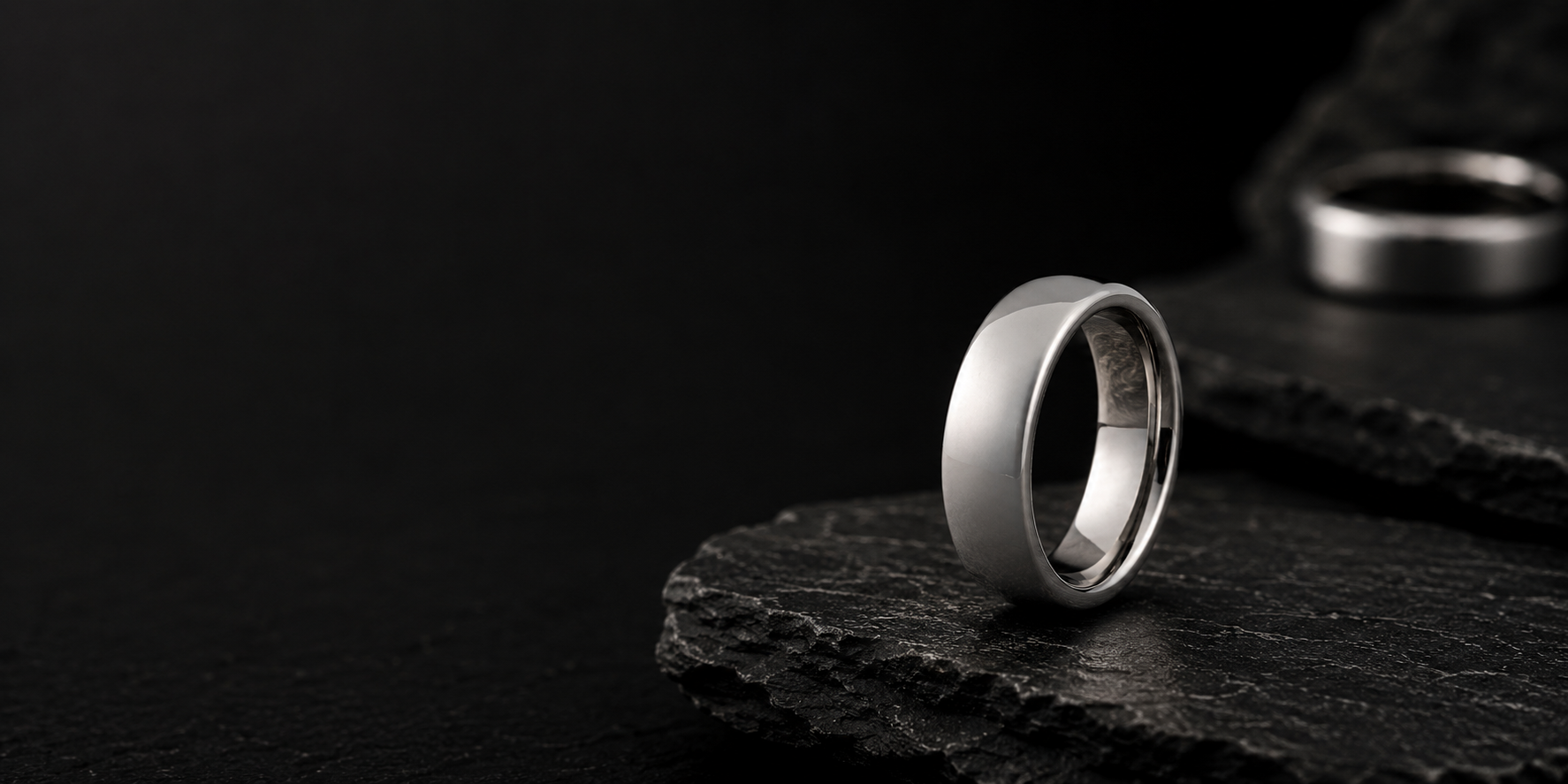 Polished silver dome tungsten wedding ring on dark slate stone with cinematic lighting and luxury masculine ecommerce styling