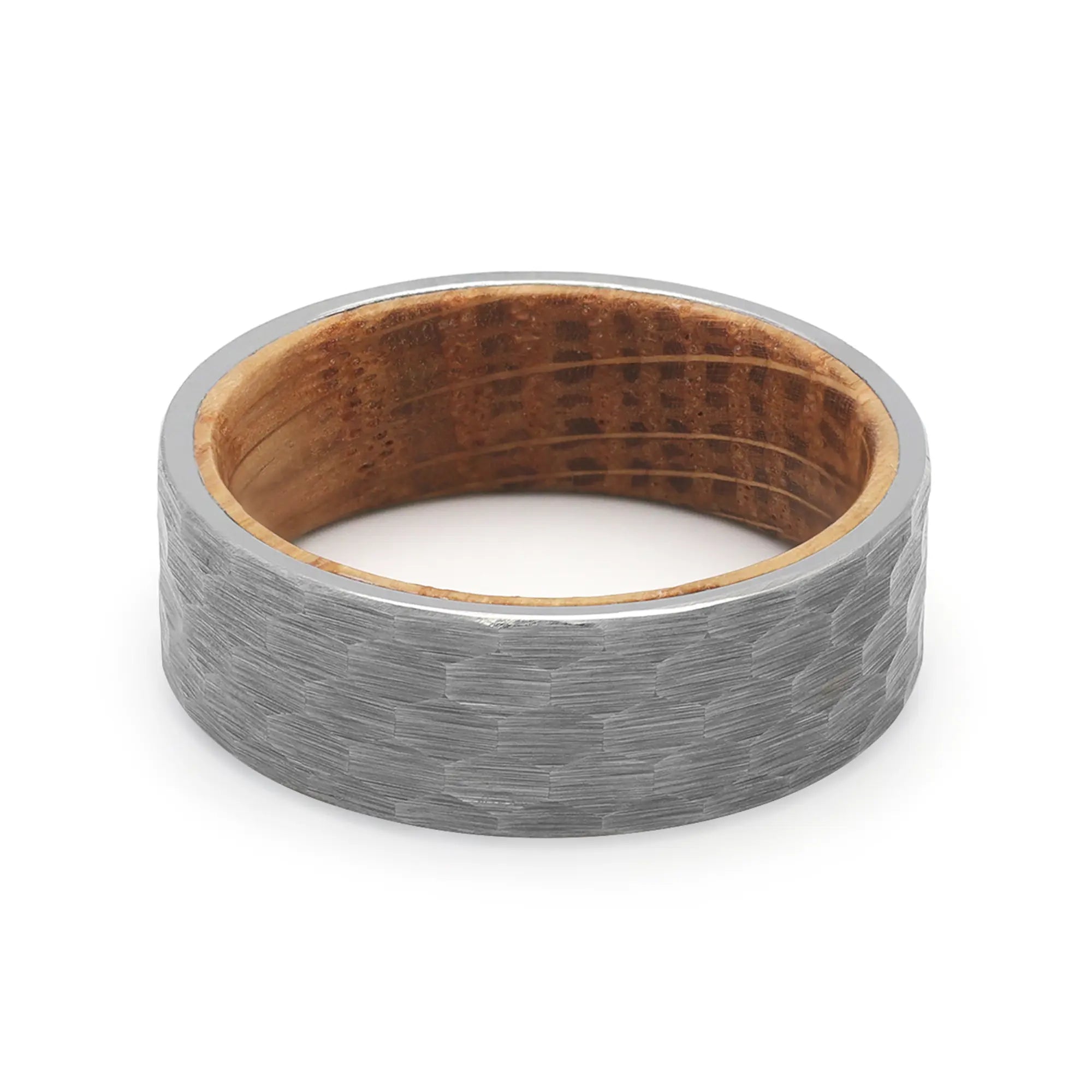 Top view of a silver hammered tungsten wedding ring with a real oak whiskey barrel wood interior.