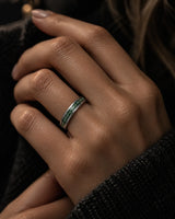 Woman wearing a slim 4mm silver tungsten wedding ring with a green moss agate inlay.