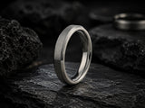 Luxury silver titanium wedding ring hero banner with dark stone textures and cinematic lighting