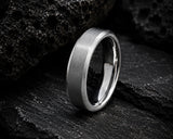 Macro close-up of a silver brushed men’s wedding ring resting on volcanic rock with dramatic cinematic lighting
